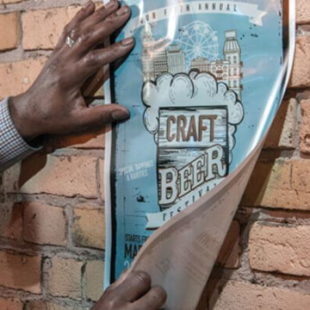 man installing a Nekoosa ClingZ adhesive free wall graphic to a brick wall.